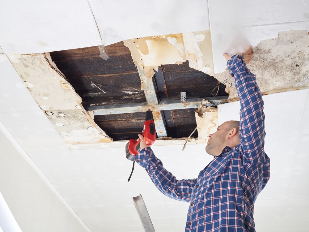 man fixing water damaged ceiling