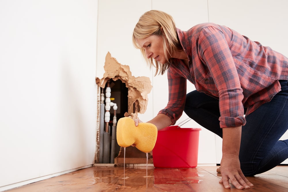woman cleaning floor from leaky house